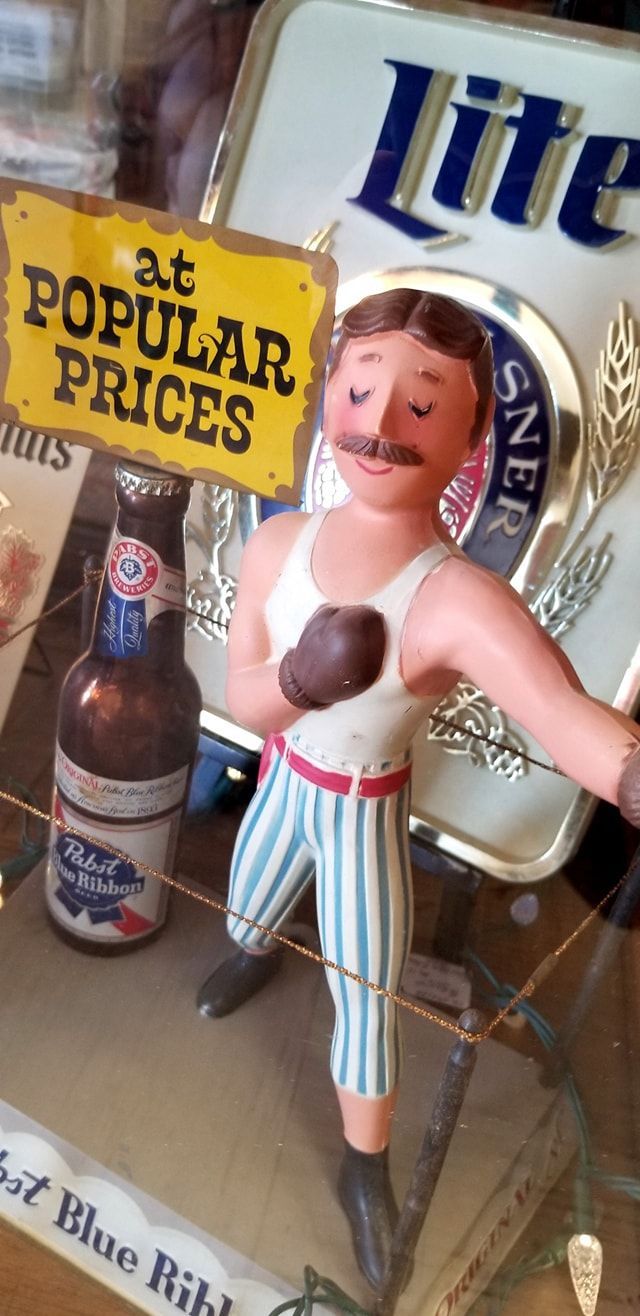 A vintage Pabst Blue Ribbon display featuring a figurine of a boxer in striped pants standing near a beer bottle.