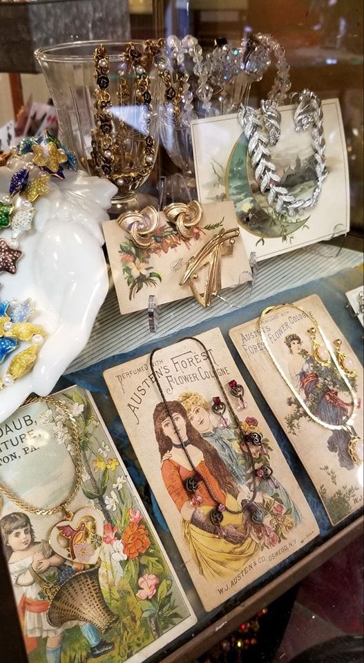 Vintage jewelry and ornate display cards arranged in a glass store case.