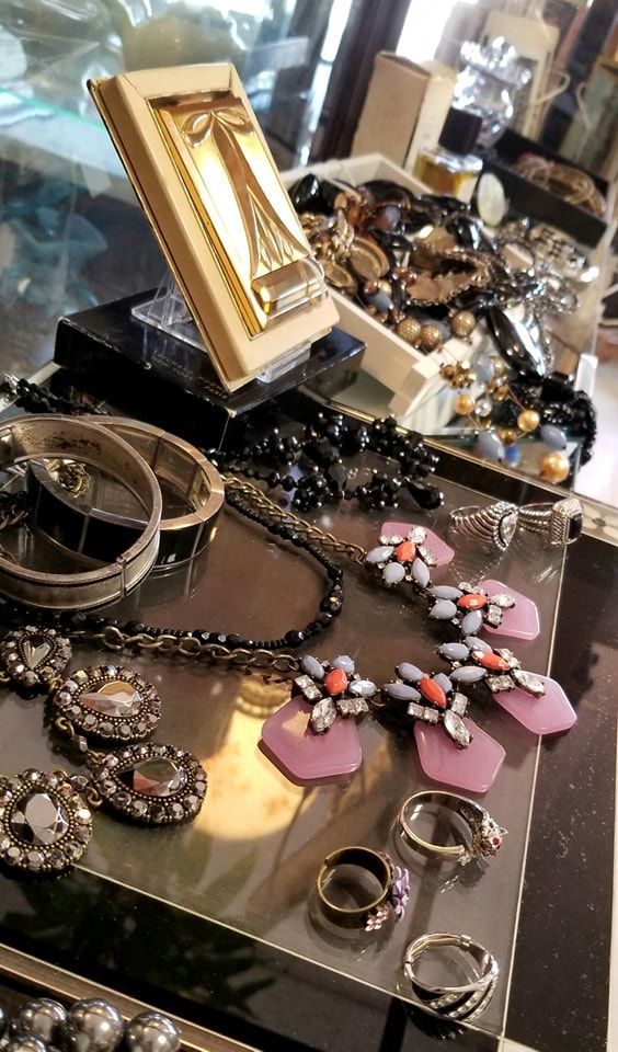 A selection of jewelry, including a gold Eiffel Tower ornament, pink and black necklaces, and several rings on a tray.