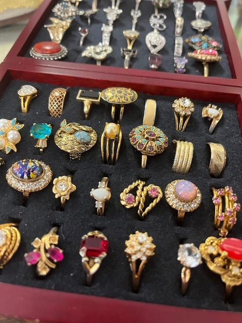 A selection of jewelry, including a gold Eiffel Tower ornament, pink and black necklaces, and several rings on a tray.