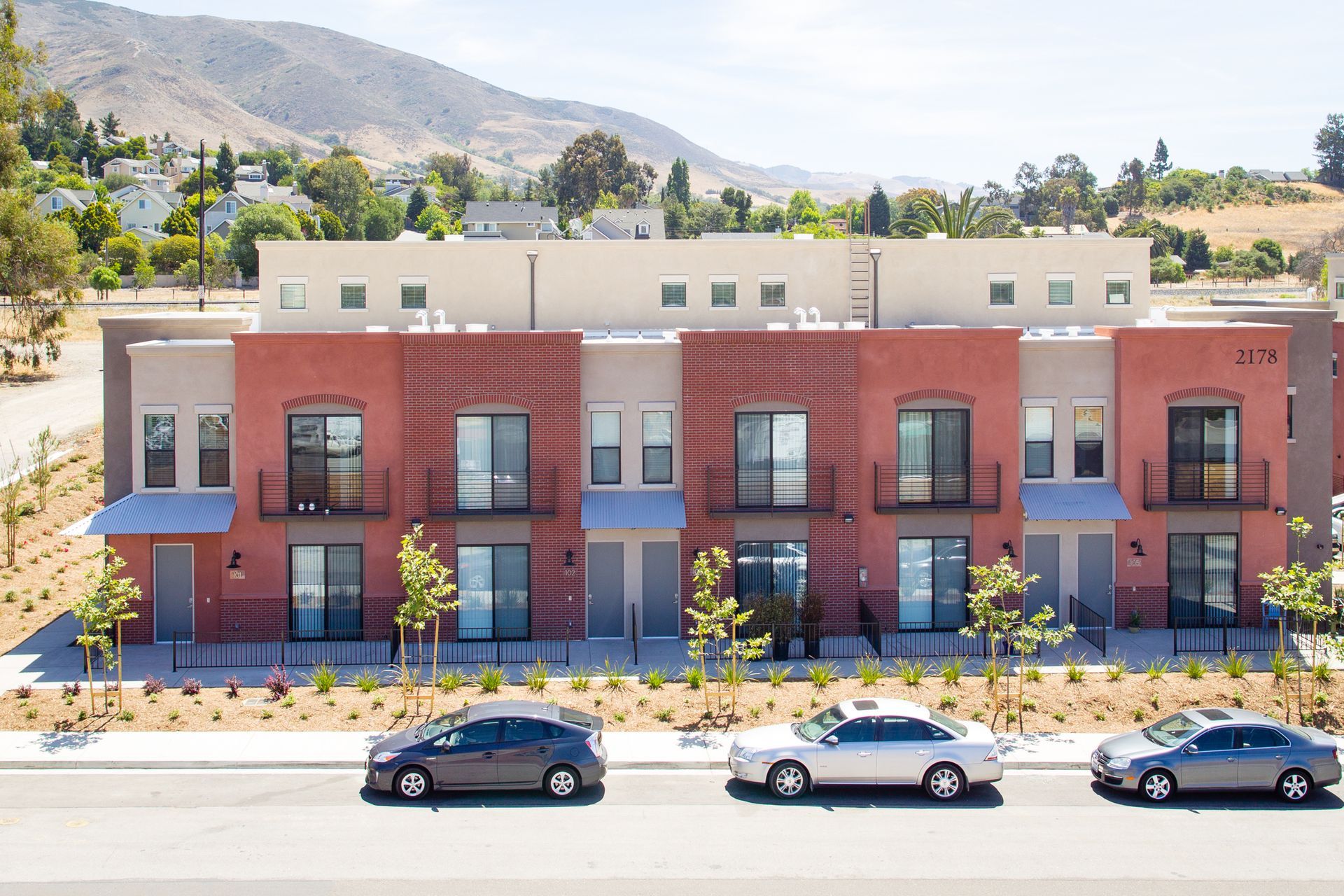 A row of apartment buildings with cars parked in front of them