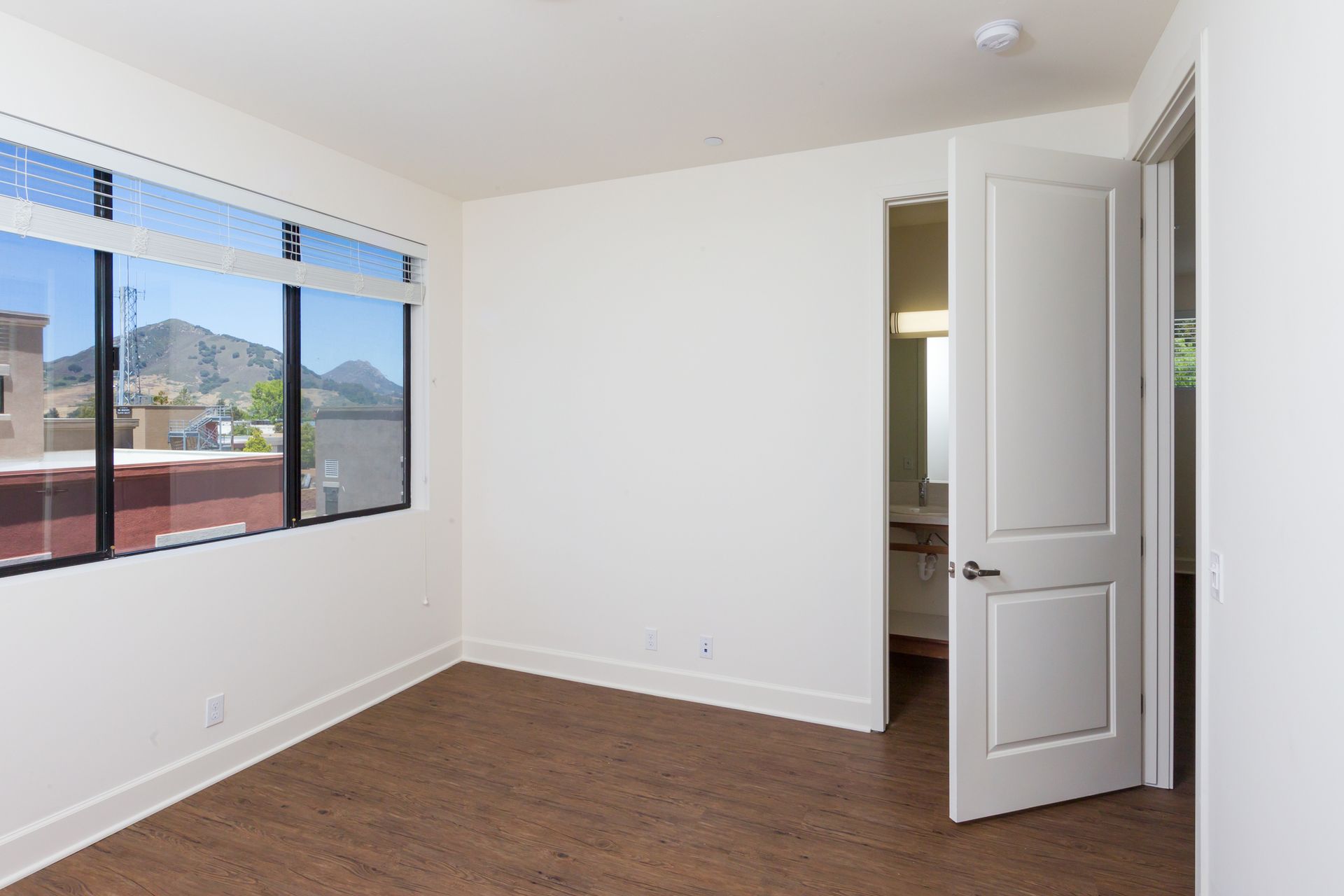 An empty bedroom with a window and a door