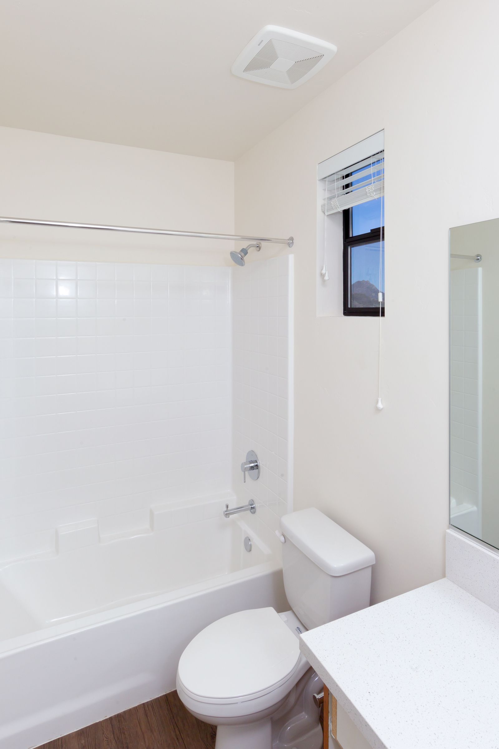 A bathroom with a toilet , bathtub and mirror.