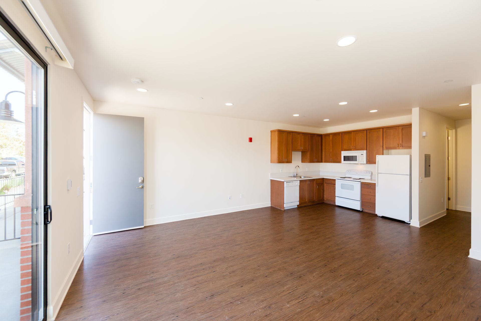 An empty apartment with a kitchen and a sliding glass door