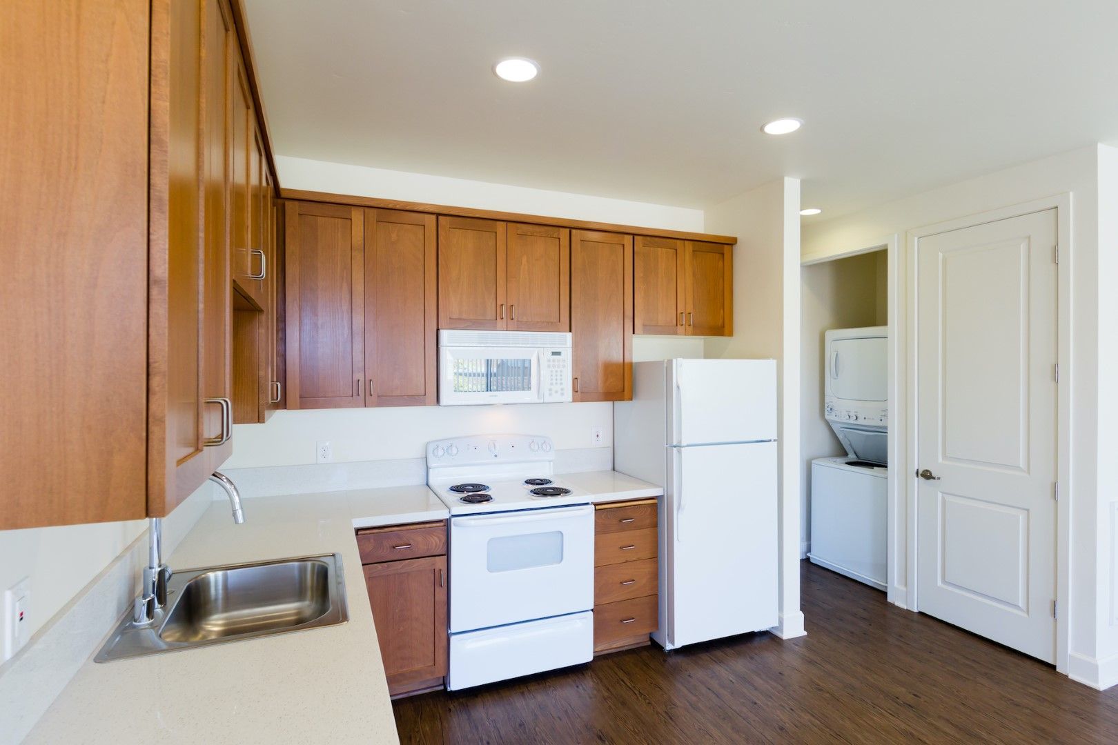 A kitchen with a stove , refrigerator , microwave and sink.