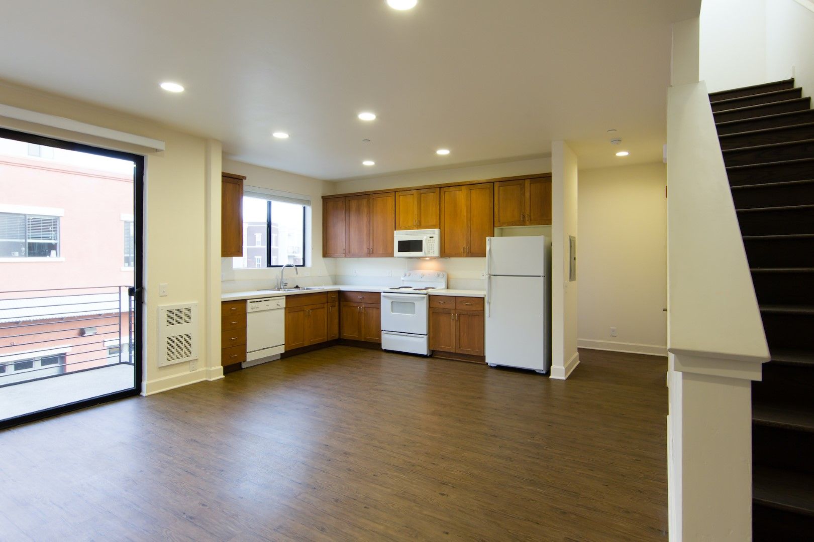 An empty kitchen with wooden cabinets and a white refrigerator