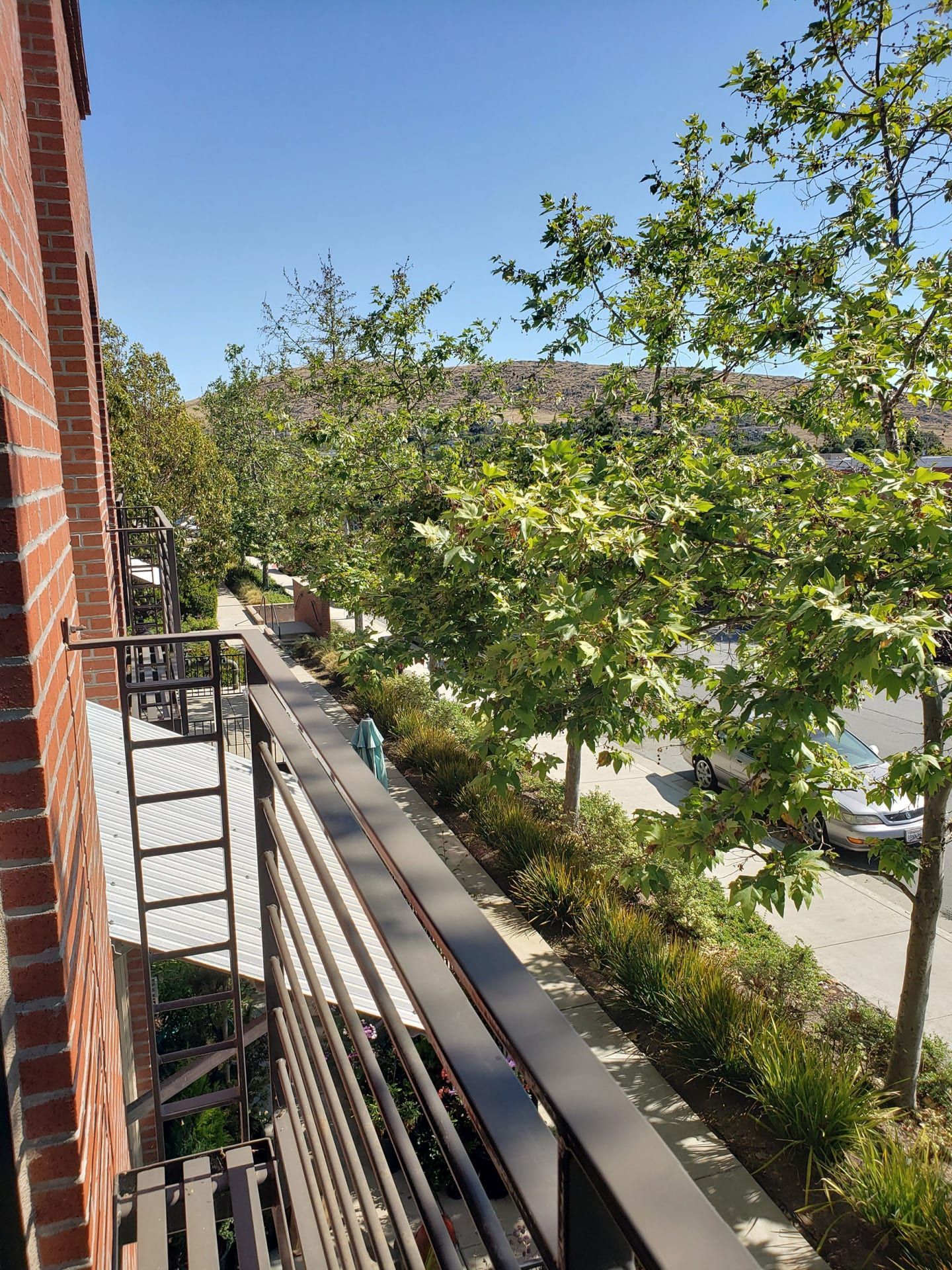 A balcony with a view of a street and trees