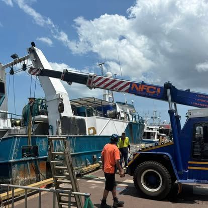 A Man Is Standing Next to A Blue Truck with A Crane Attached to It — Northern Franna Cranes NT in Noonamah, NT