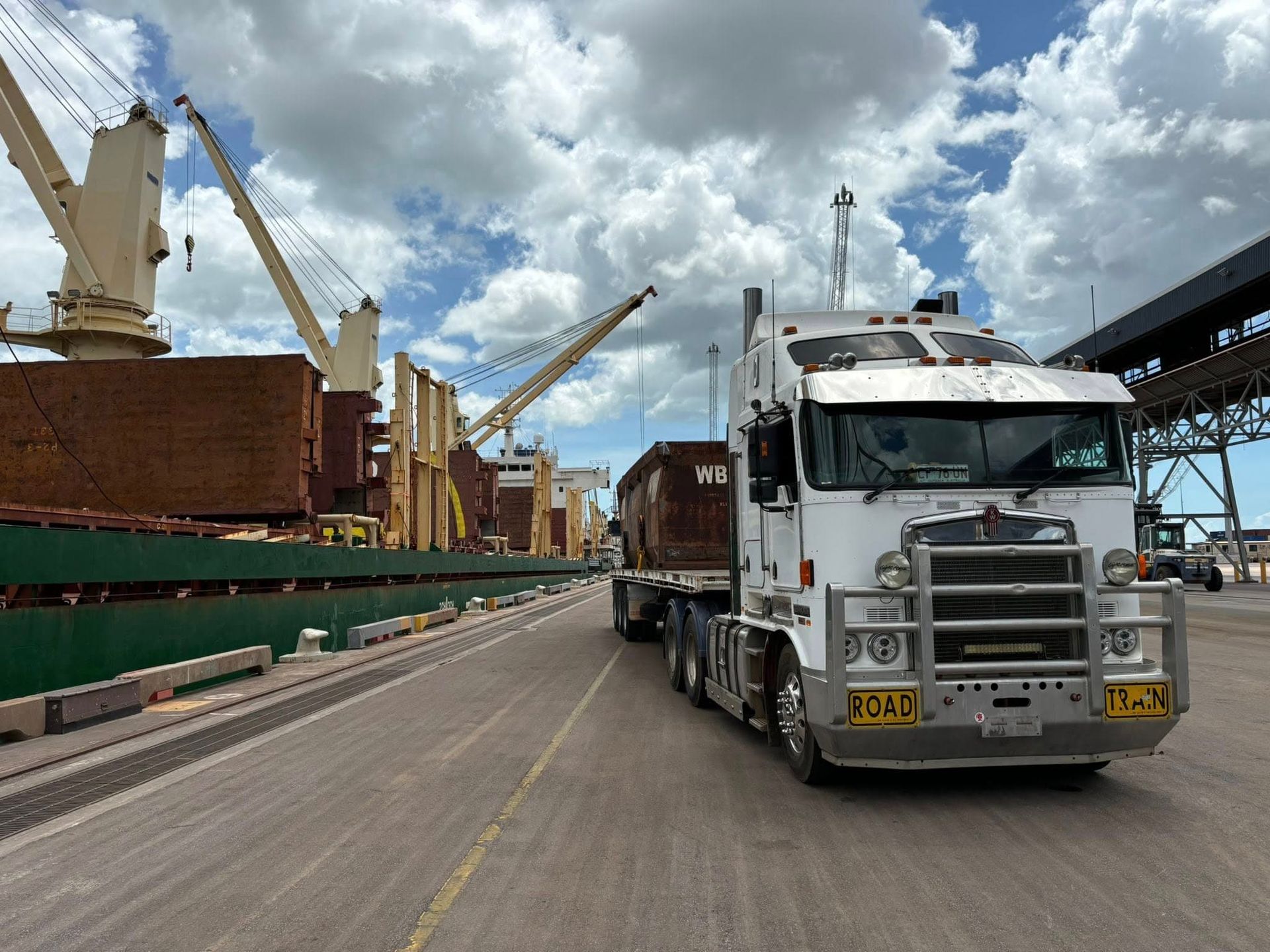 A Truck Is Driving Down a Road in Front of A Large Ship — Northern Franna Cranes NT in Noonamah, NT