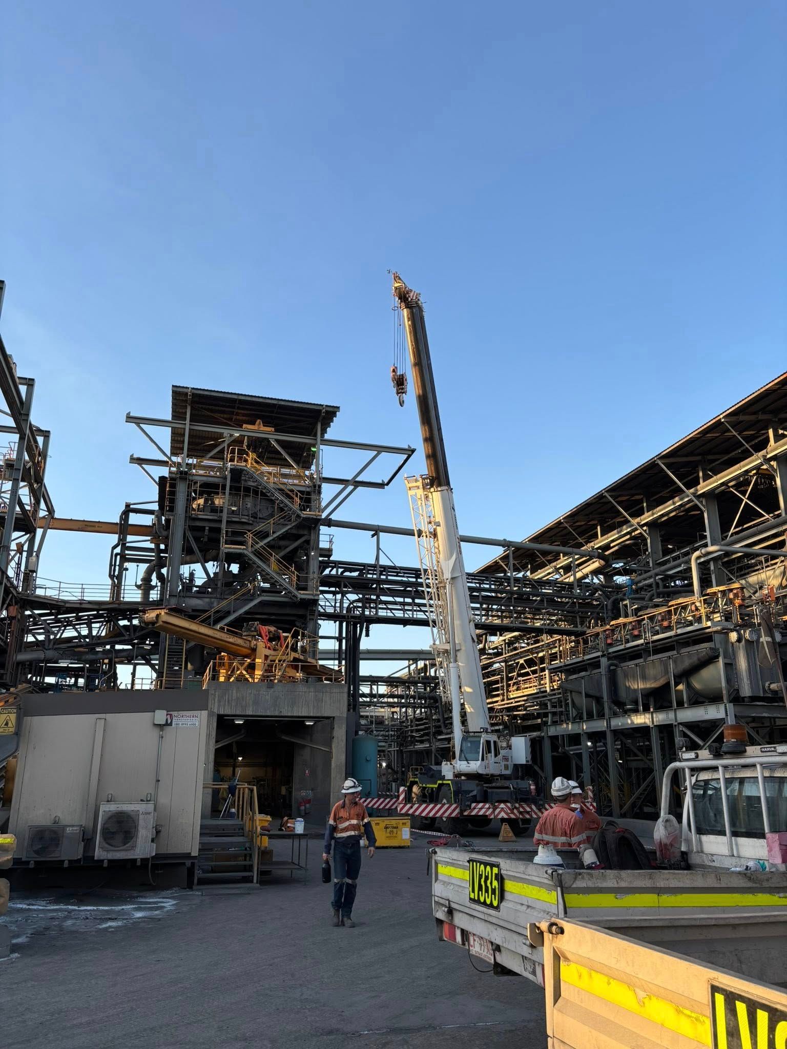 Image of a crane on a work site. Workers and scaffolding also captured.