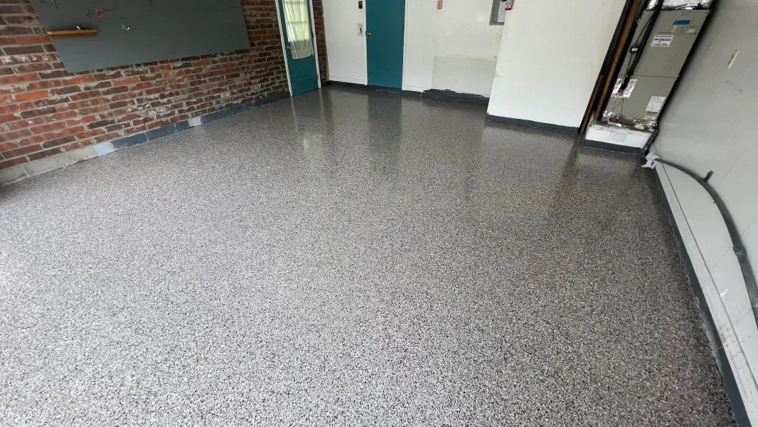 Garage floor with a glossy, speckled gray epoxy finish. 