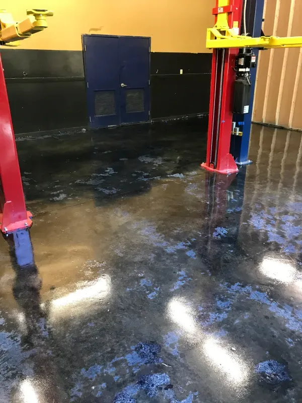 Garage floor with a blue and black epoxy coating, showing peeling or wear.