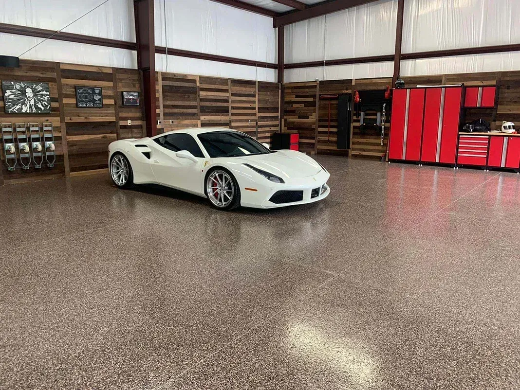 White sports car parked in a garage with red cabinets and a wood-paneled wall. 