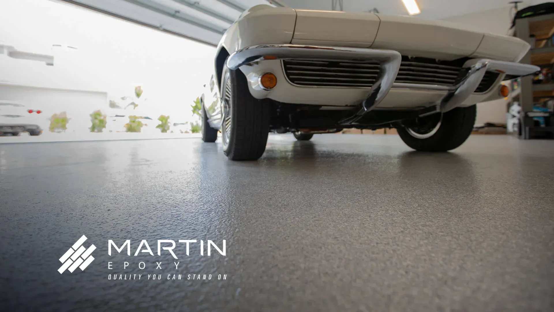 White classic car parked in a garage with a speckled gray epoxy floor.