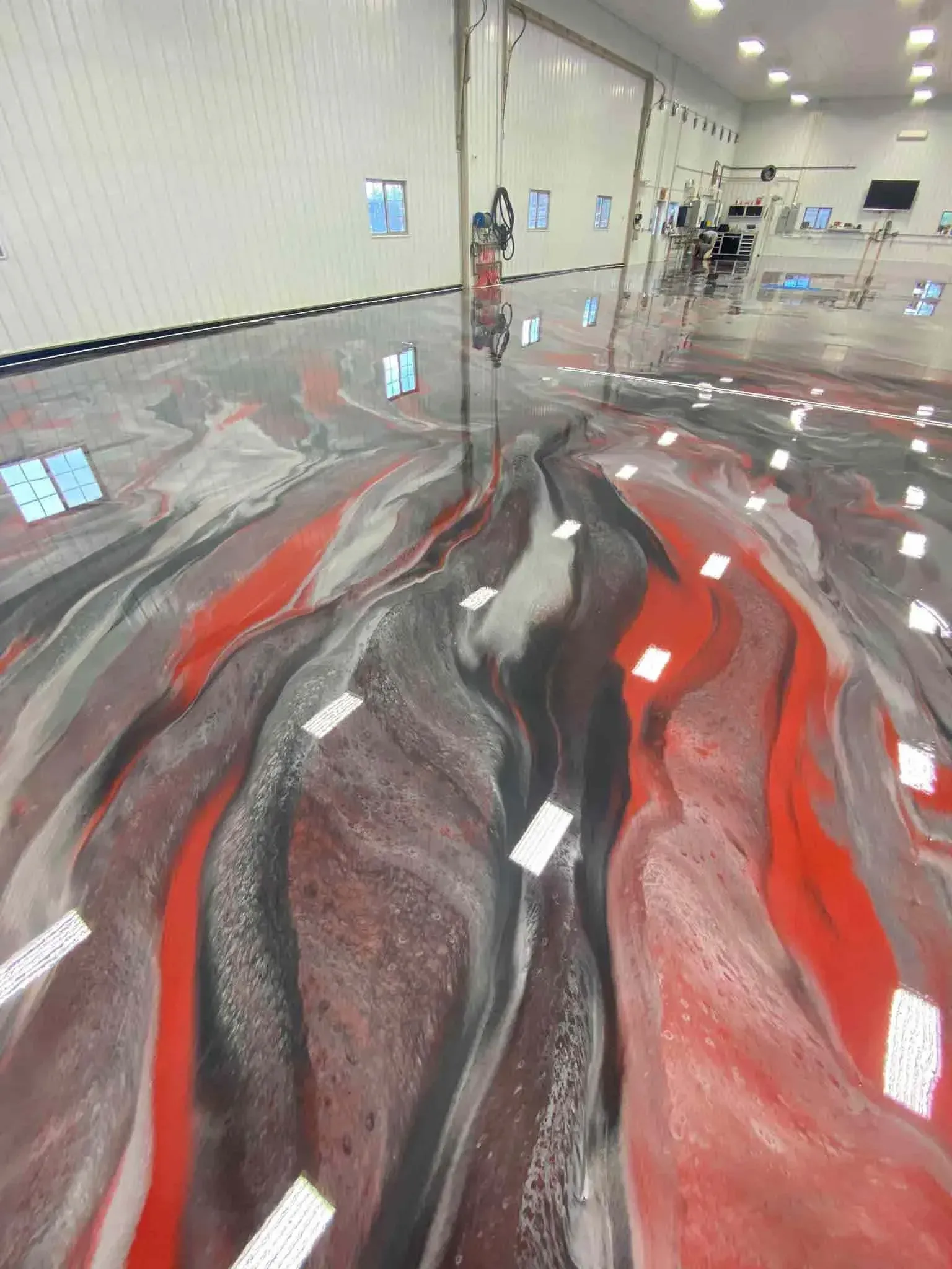 Red, gray, and black epoxy floor in a large, white-walled room.