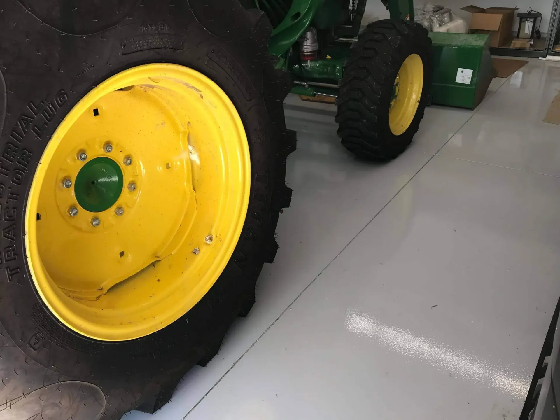 Yellow and green tractor wheels on a light-colored floor. 