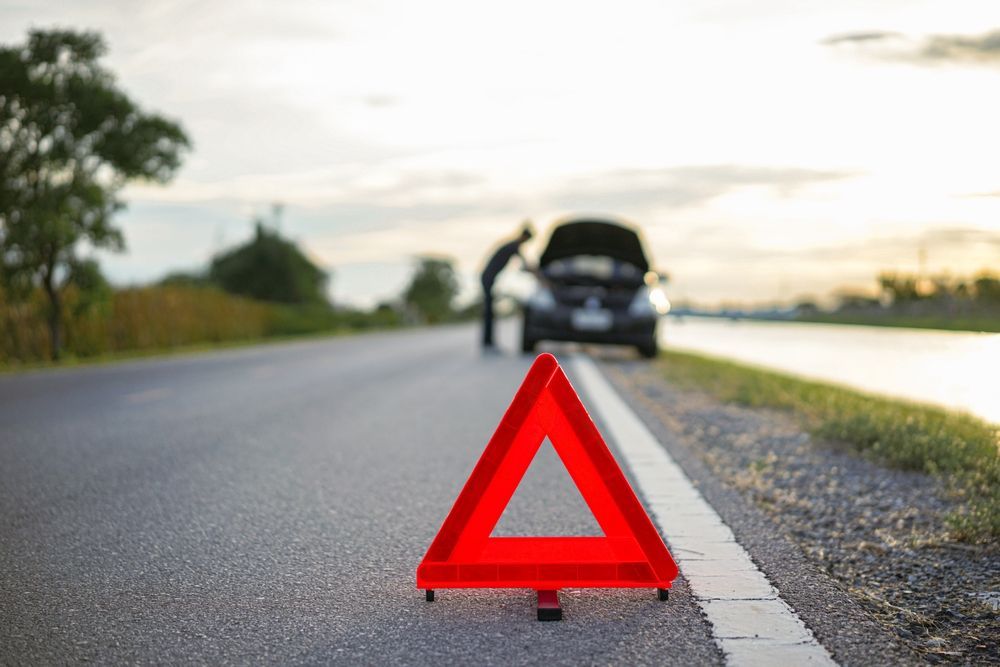 man leaning over car with emergency triangle set on road