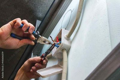 A person is working on a wall with a pair of pliers.