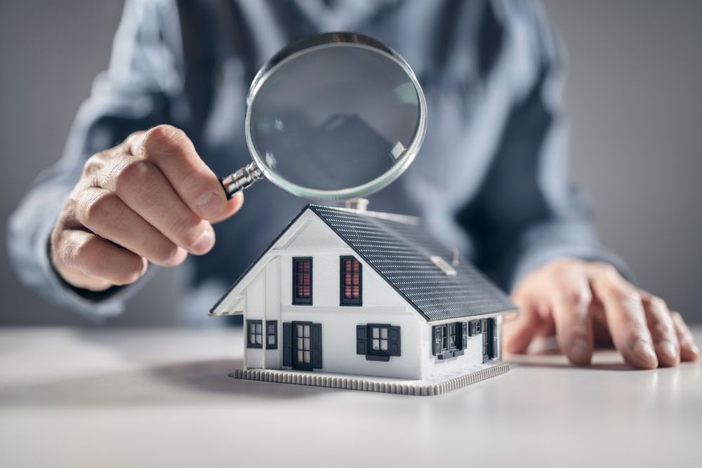 A man is looking at a model house with a magnifying glass.