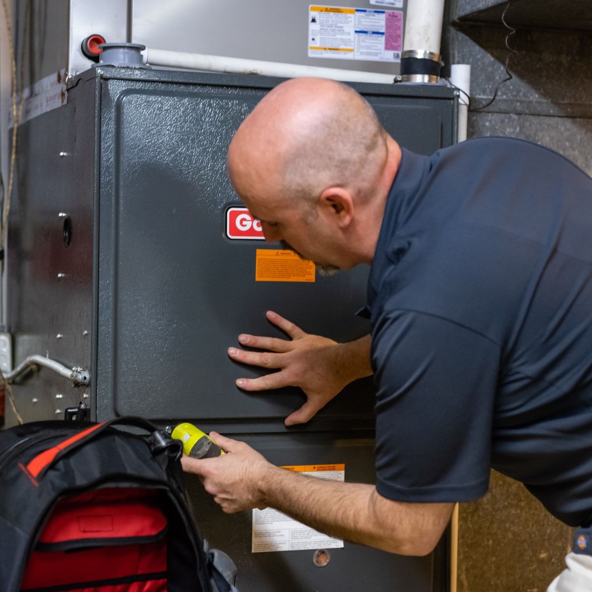 A man in a blue shirt is working on an air conditioner