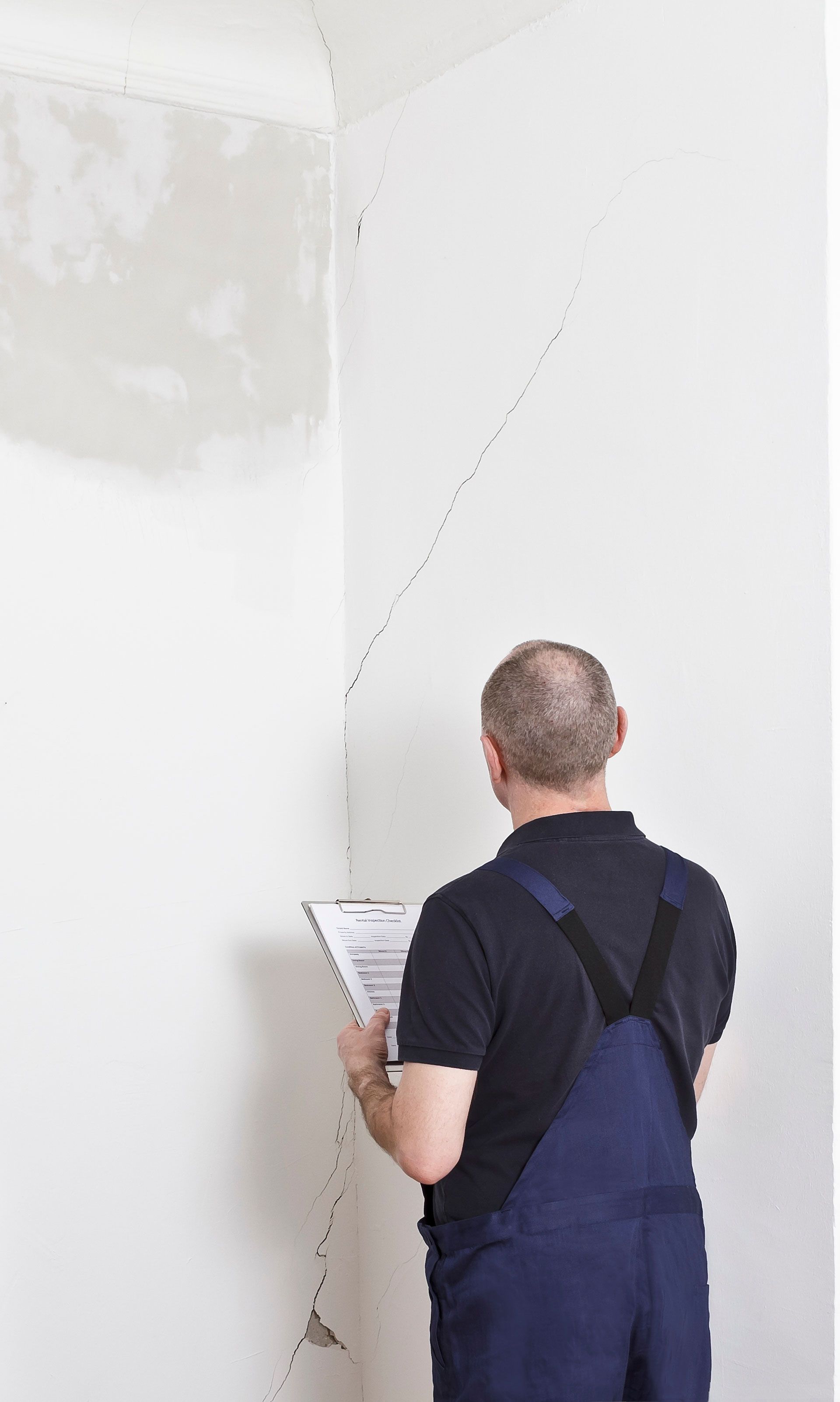 A man is standing in a corner of a room looking at a piece of paper.
