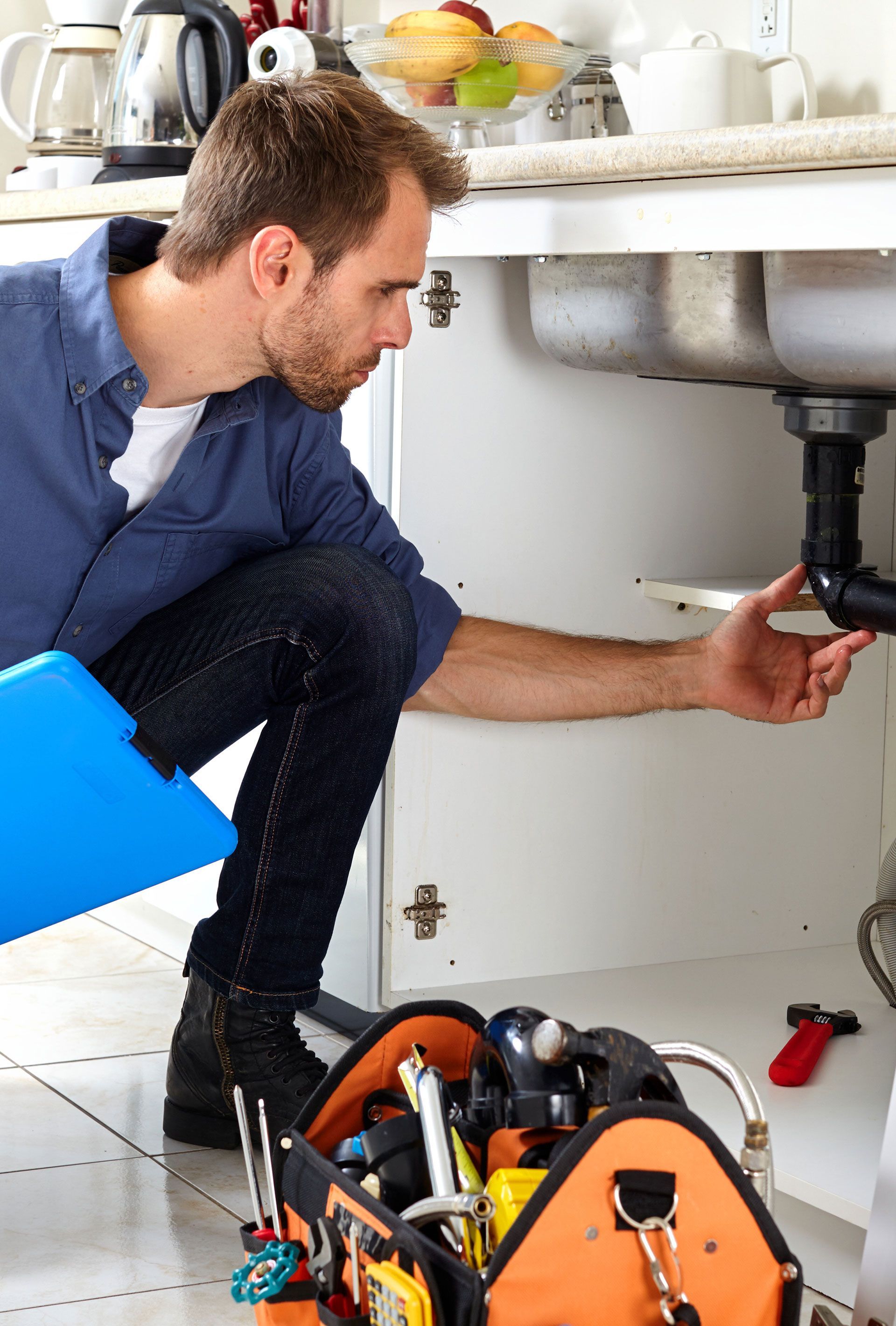 A man is fixing a sink in a kitchen.