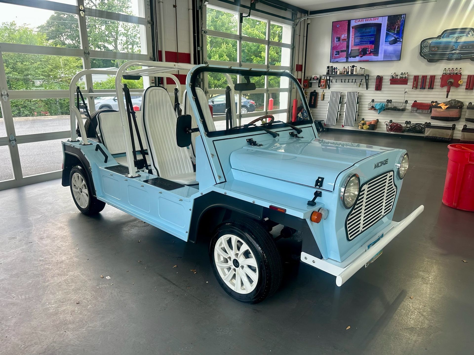 Light blue vintage off-road buggy in a garage, with roll bars and white seats