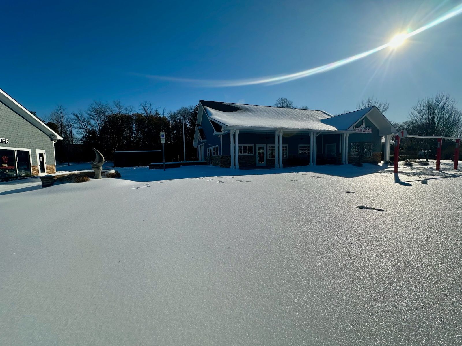 Snow-covered house under bright sun with blue sky and long shadows.