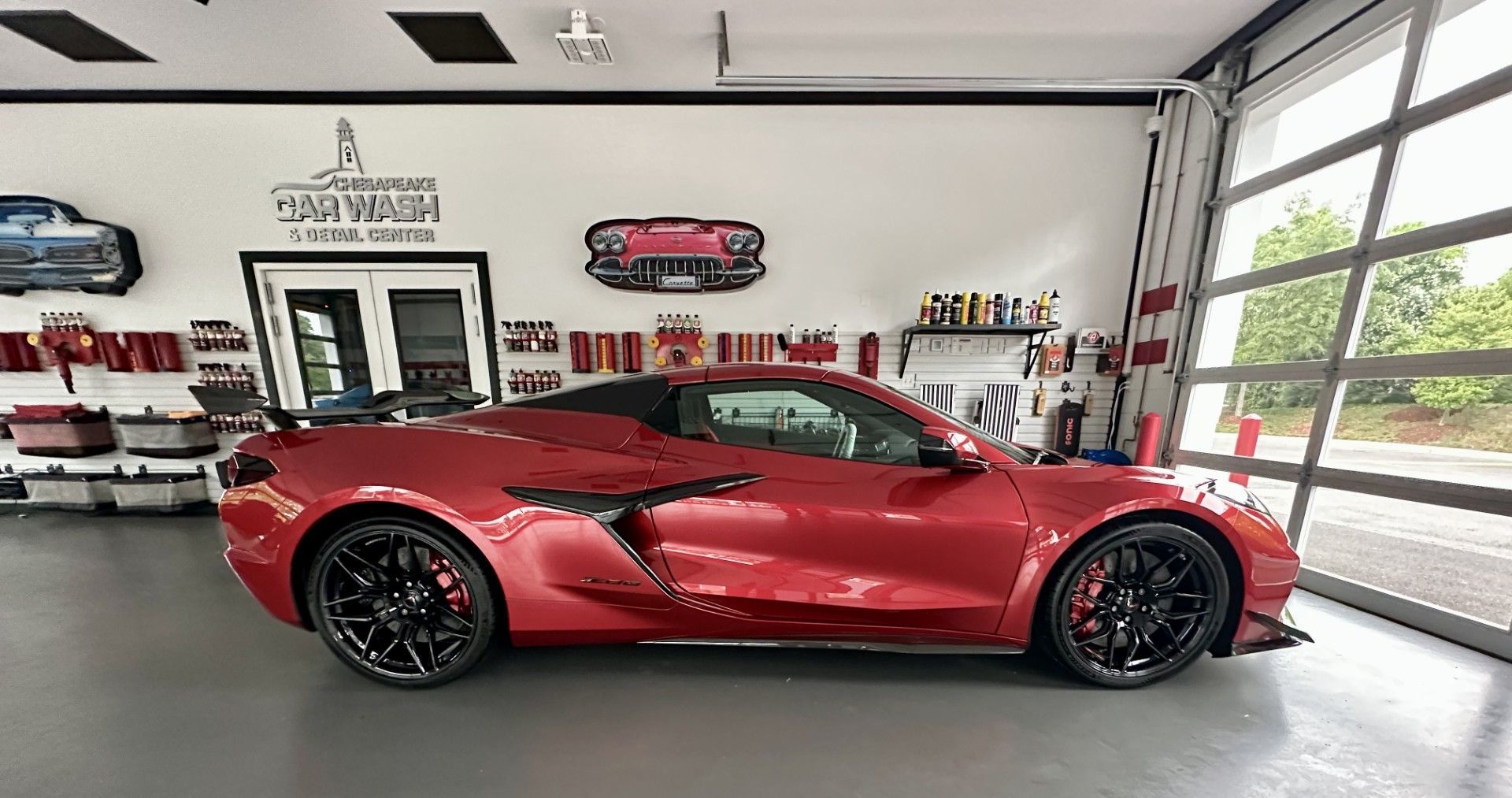 Red sports car in a bright showroom with large windows and wall displays