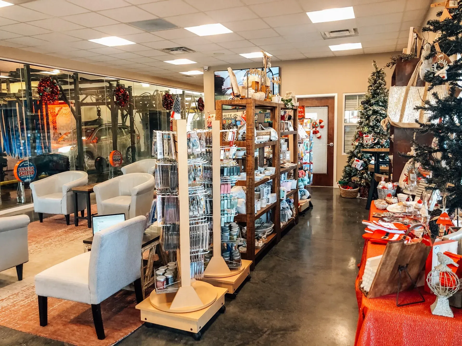 Interior of a shop with displays of merchandise and seating area, decorated for Christmas.
