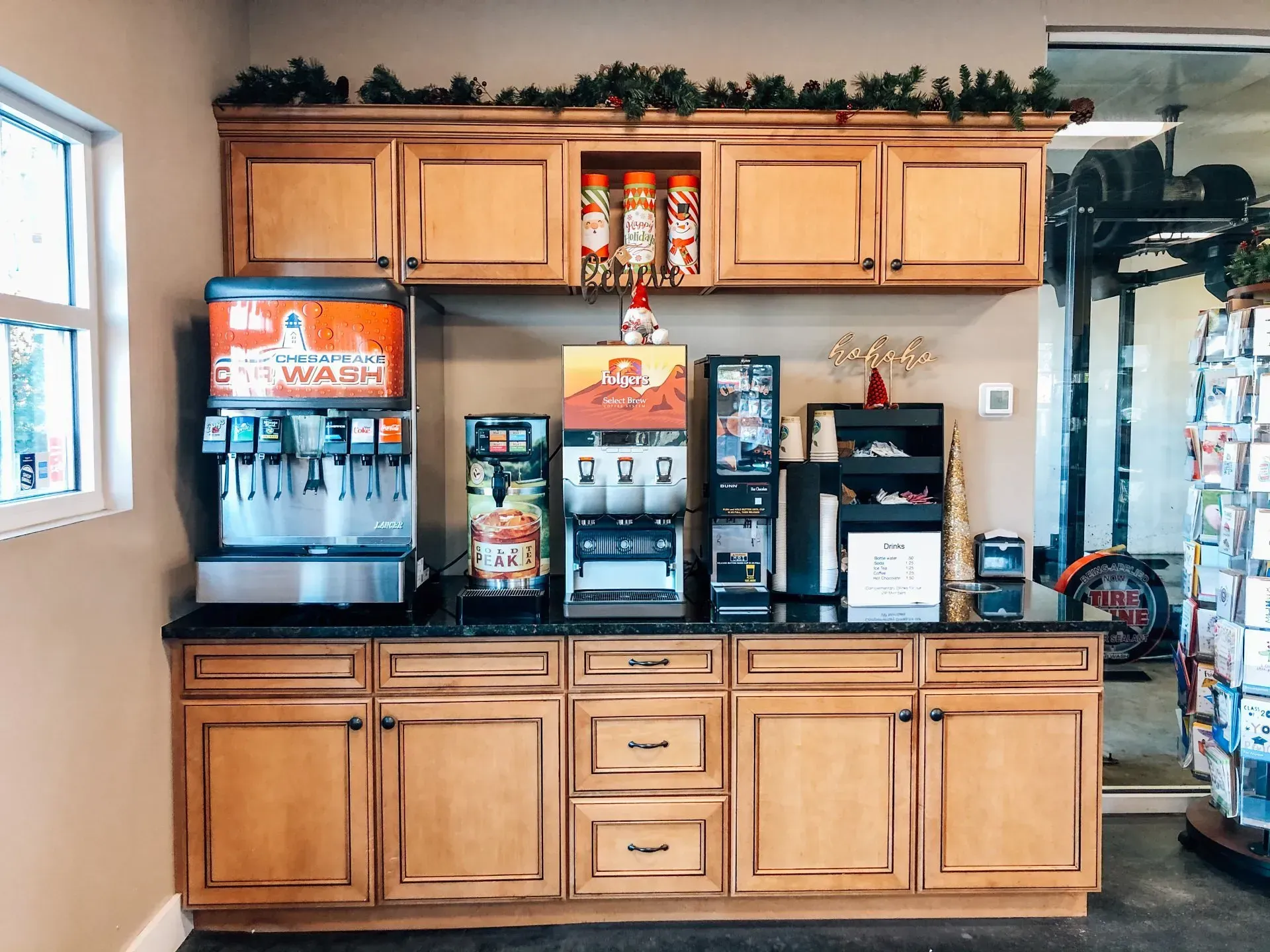 Coffee and drink station with light brown cabinets, drink machines, and holiday decor.