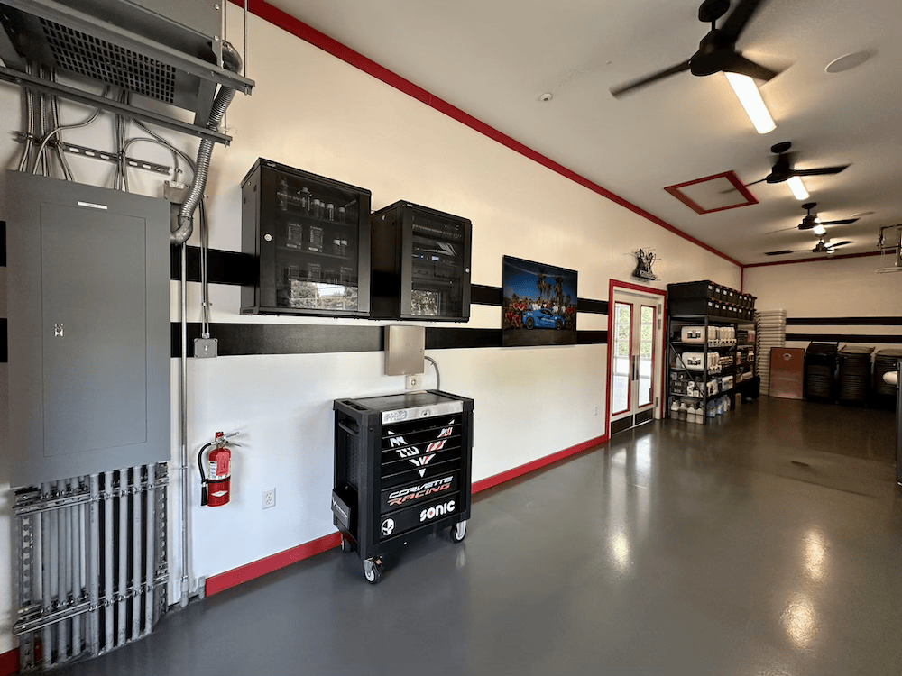 Industrial room with electrical panels, wall-mounted screens, and storage cabinets on a polished concrete floor.
