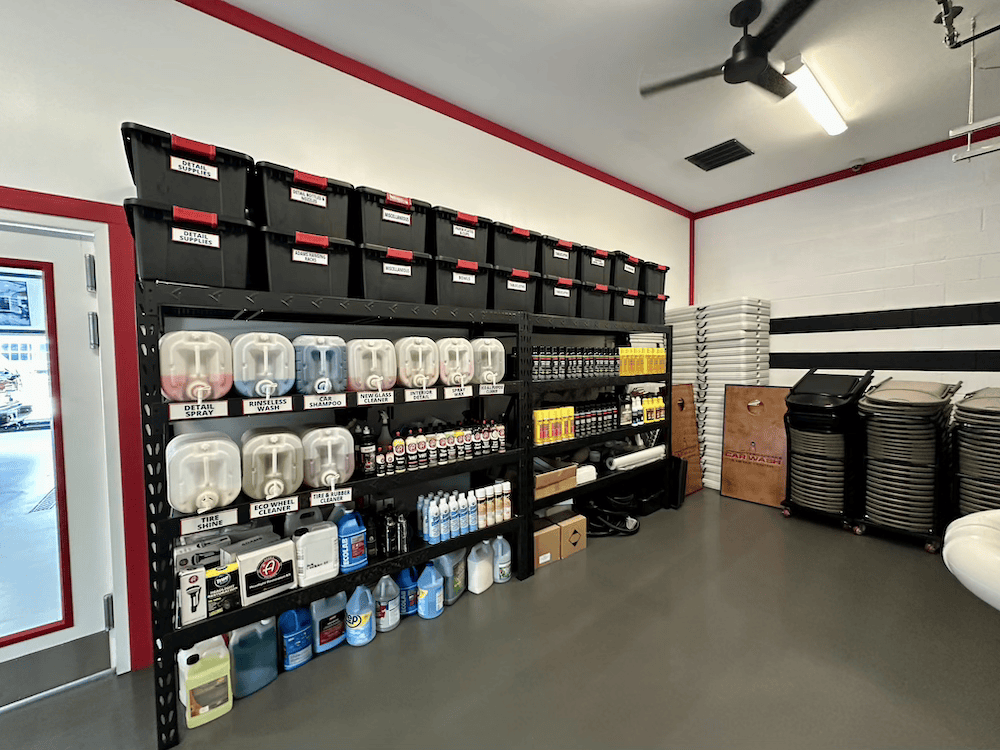Retail store interior with shelving of storage bins, appliances, and stacked mats on a gray floor