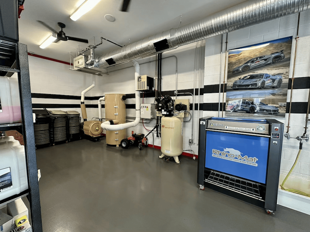Industrial workshop with ducting, equipment, and a blue machine on a gray floor