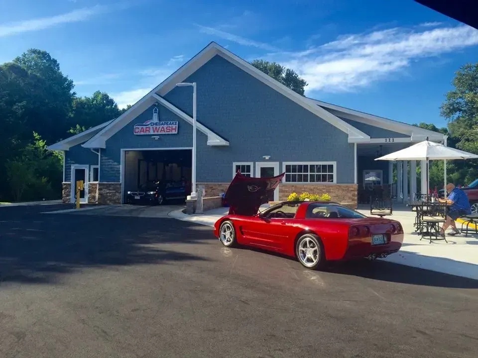 Red Corvette convertible parked at a blue car wash on a sunny day.