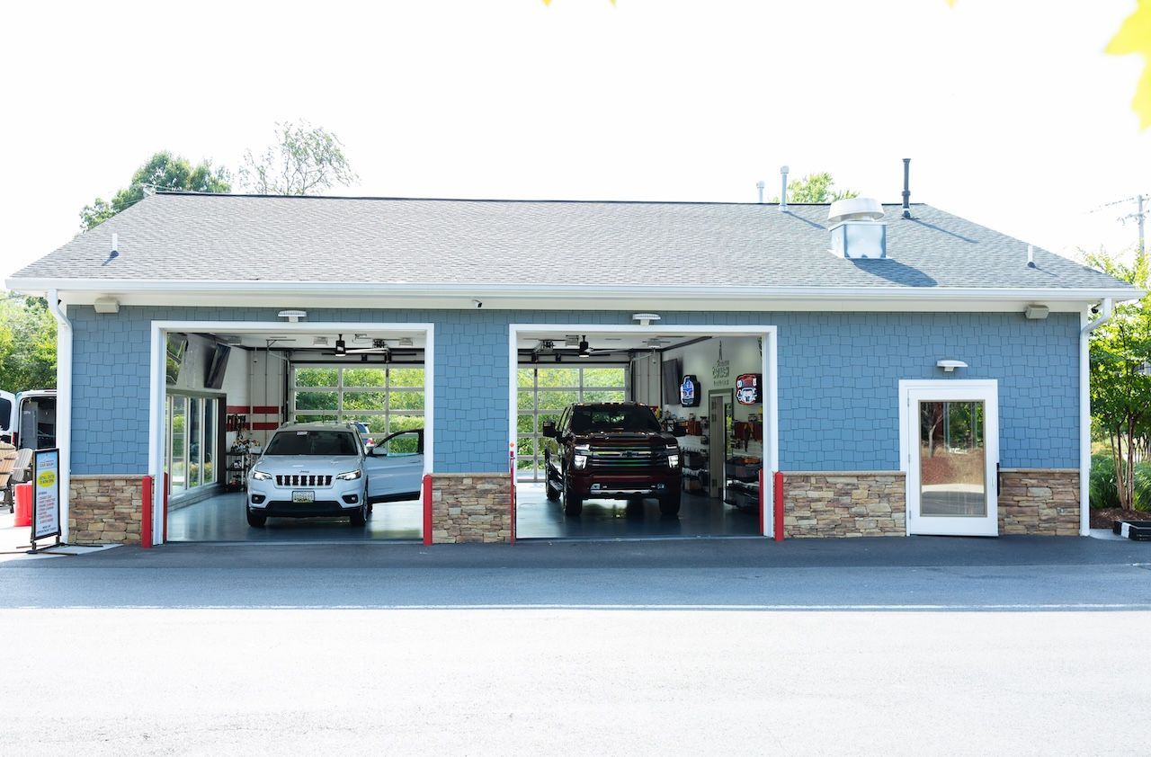 Blue auto repair shop with two open bays and cars inside