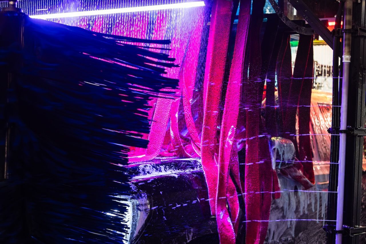 Neon pink and purple lights reflecting on wet glass or plastic in a dark urban scene