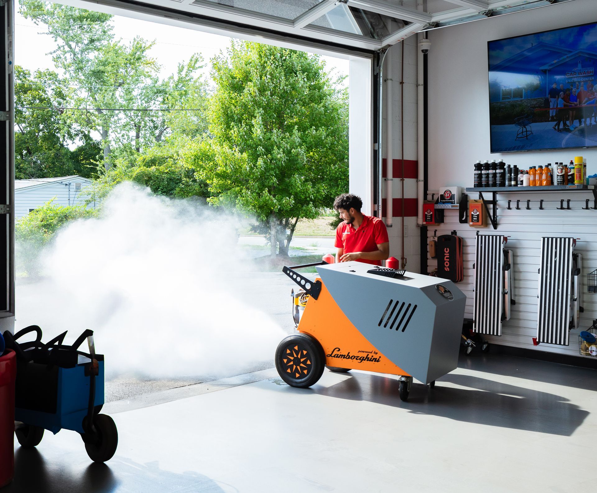 Person operating a fog machine in a garage, filling the open doorway with thick white smoke.