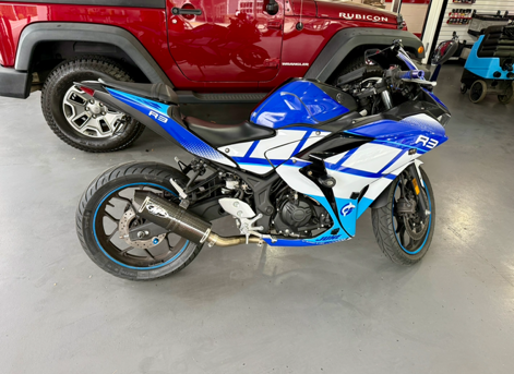 Blue and white sport motorcycle parked indoors beside a red pickup truck