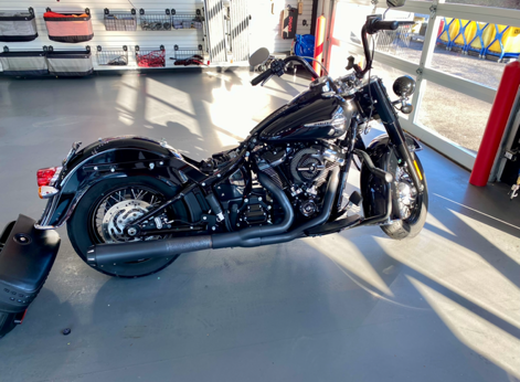 Black custom motorcycle parked indoors in a bright showroom, side view