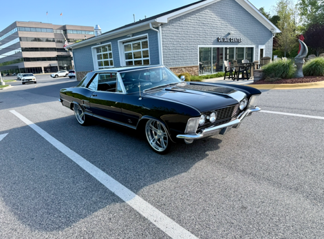 Classic black vintage car parked outside a building on a sunny street.