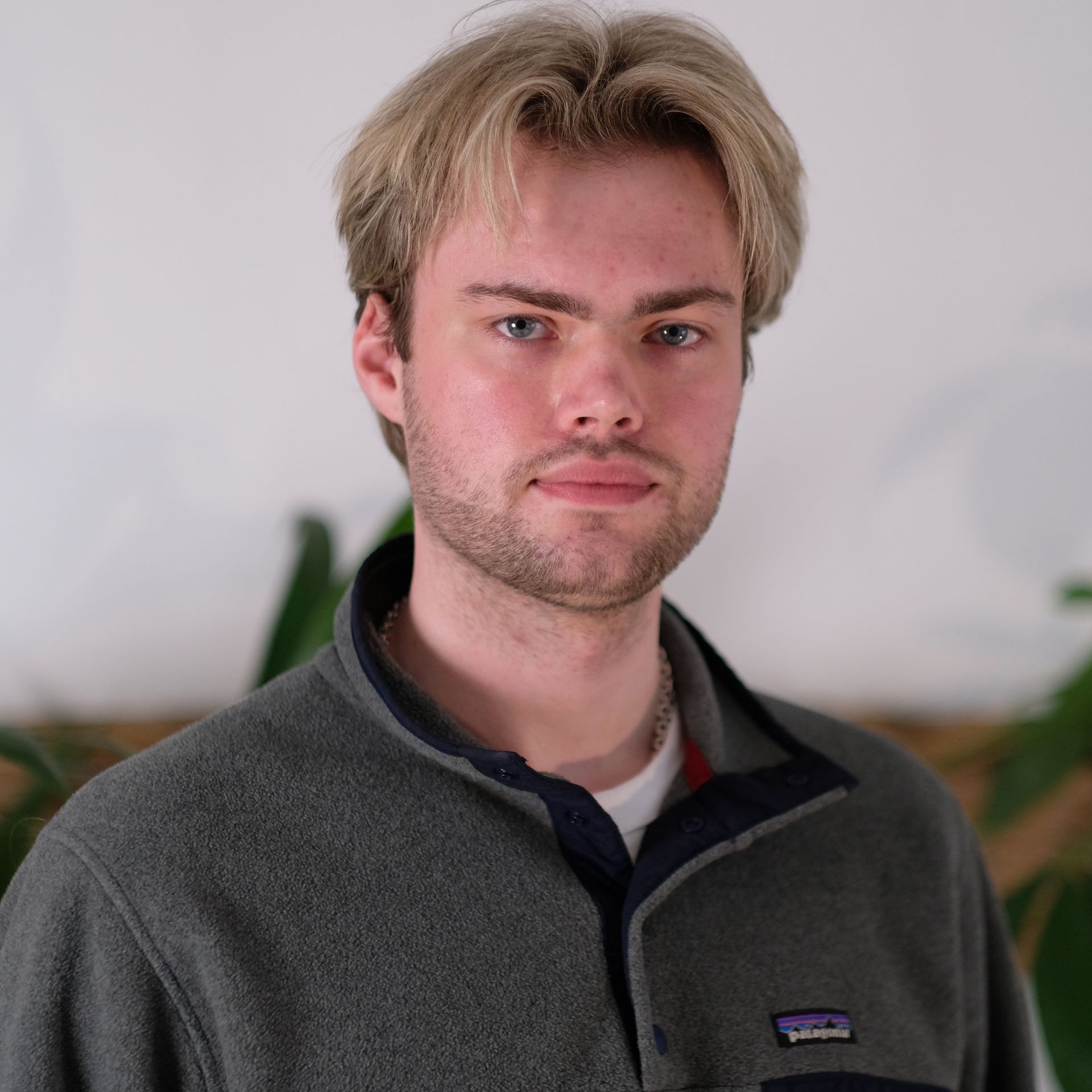 Headshot: a white man with blond hair and stubble looks into the camera wearing a fleece with a zip