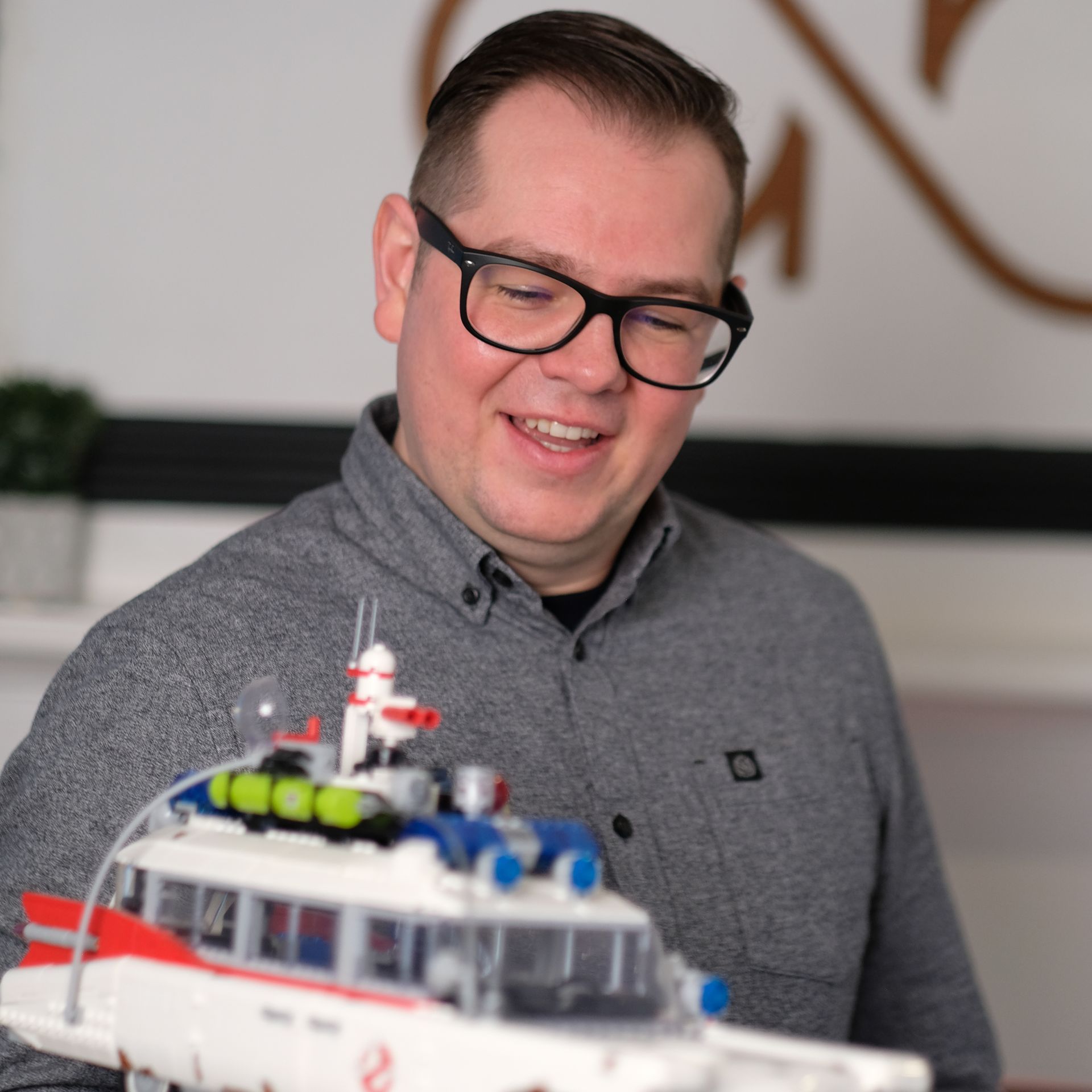 Headshot: a white man with dark hair and glasses holds up a lego model