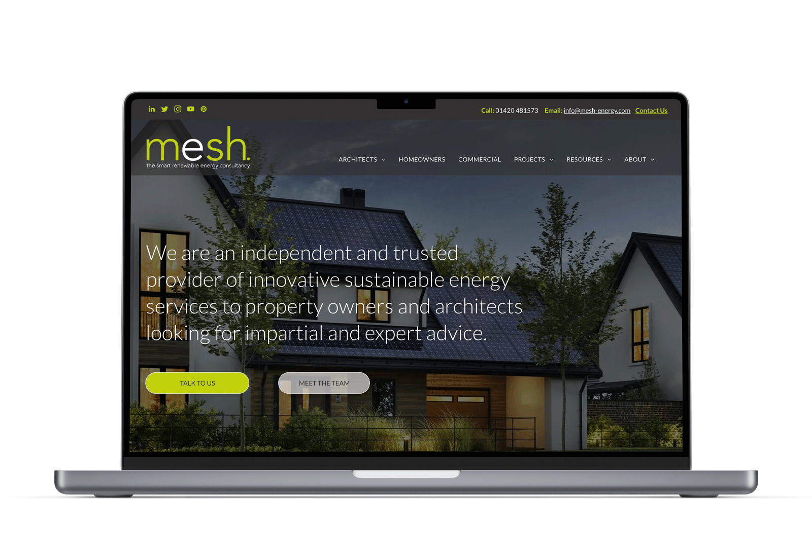 A laptop sits open displaying the Mesh Energy website which features the backdrop of some residential homes.
