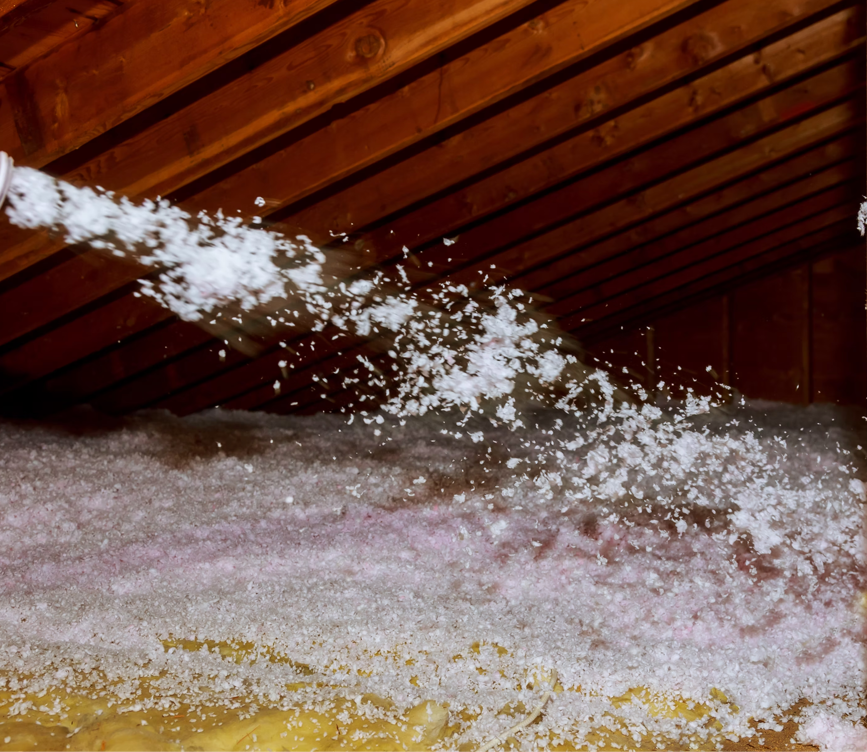 A hose is spraying white foam into an attic