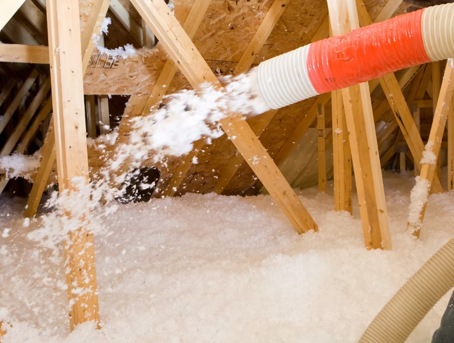 A person is blowing insulation into the attic of a house
