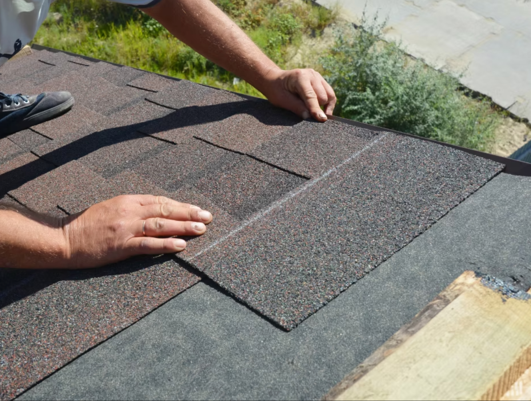 A person is laying shingles on a roof.