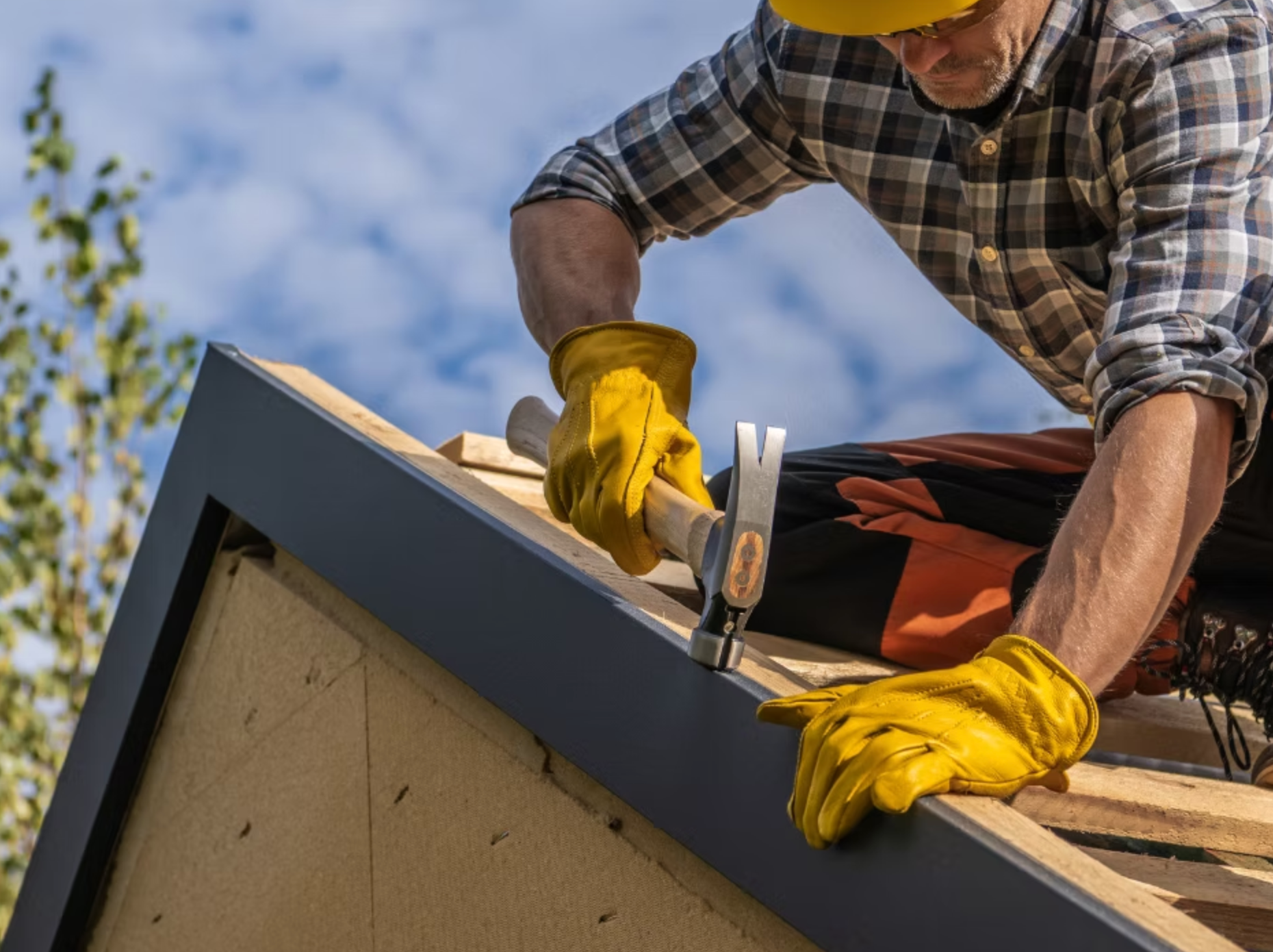 A man is working on a roof with a hammer and nails.