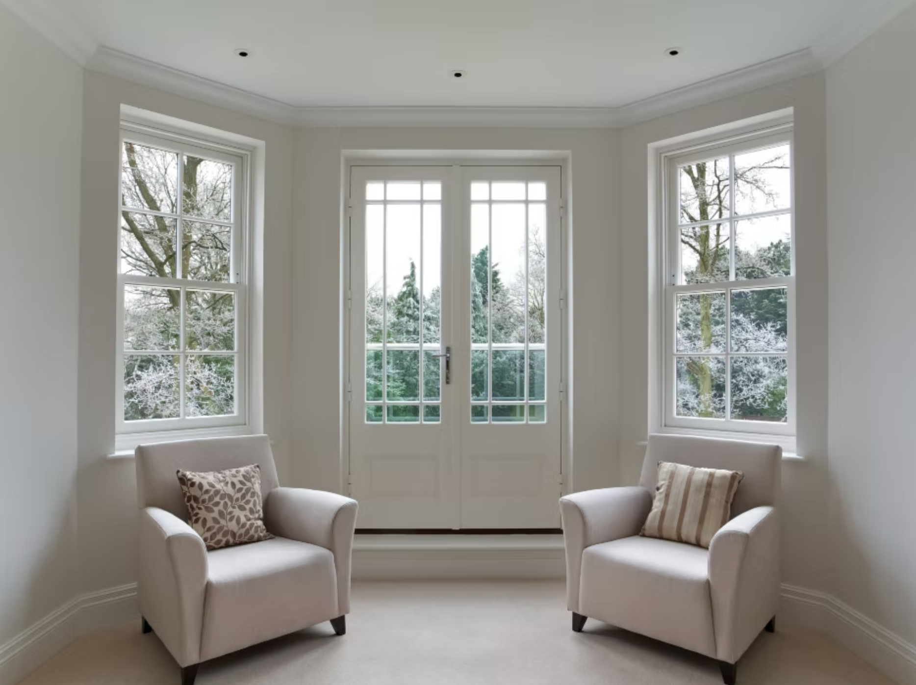 A living room with two chairs and two windows