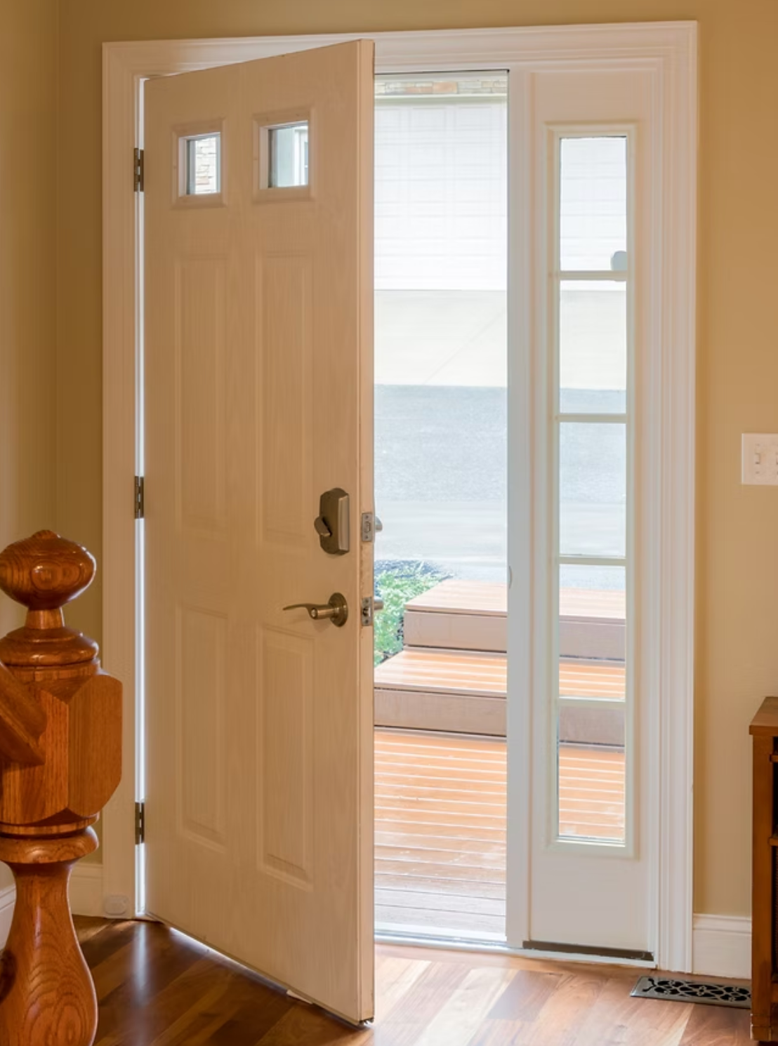 A white door with a view of the ocean is open